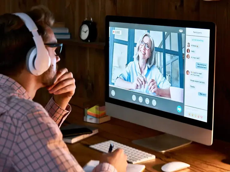 Ein Mann sitzt vor einem Bildschirm und nimmt an einem Online-Coaching teil 
