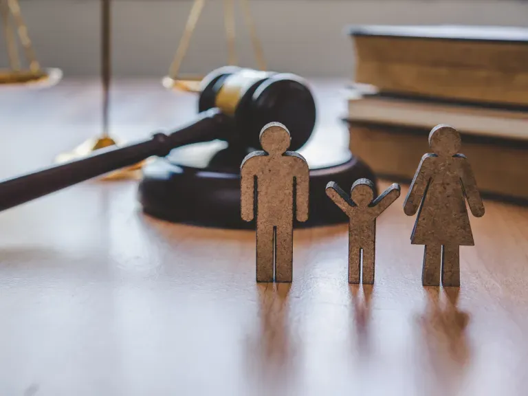 Holzfiguren Vater, Mutter, Kind - im Hintergrund ein Richter-Hammer