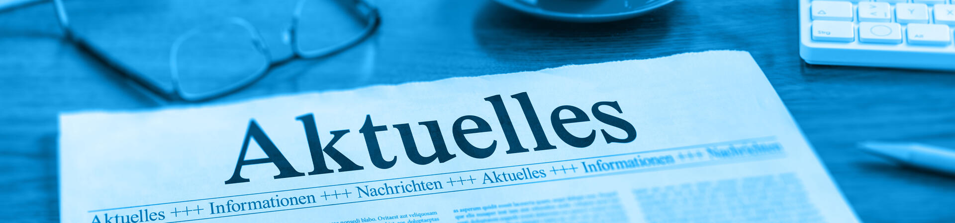 Eine Zeitung auf einem Tisch mit der Überschrift Aktuelles