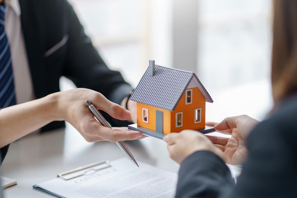 Makler überreicht Käuferin ein Modellhaus nach Abschluss des Immobilienkredits.