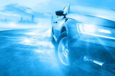 Teilausschnitt von der linken Frontseite eines Autos, das um eine Kurve fährt